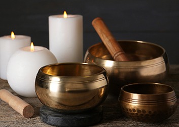 Golden singing bowls, mallets and burning candles on wooden table